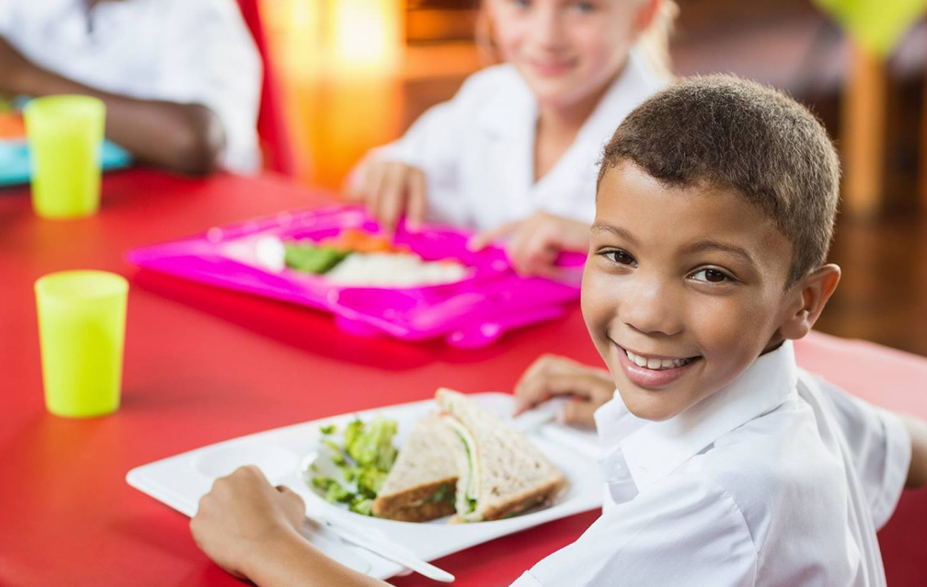 Small boy smiling at camera because he's been provided with a meal